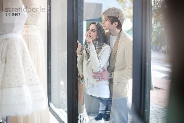 Junges Paar beim Schaufensterbummel  Blick durch die Ladenfront