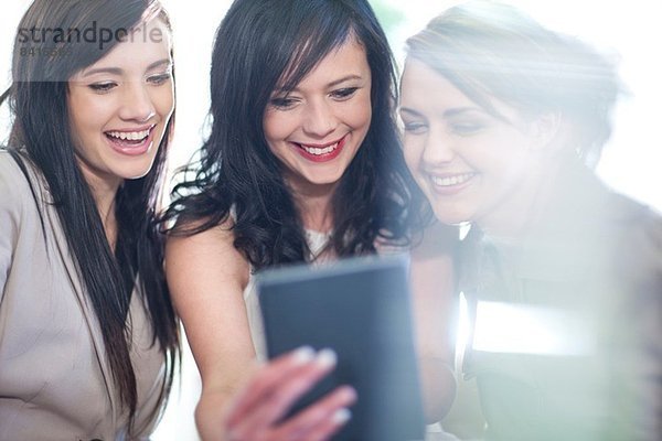 Drei Freundinnen beim Betrachten des digitalen Tabletts