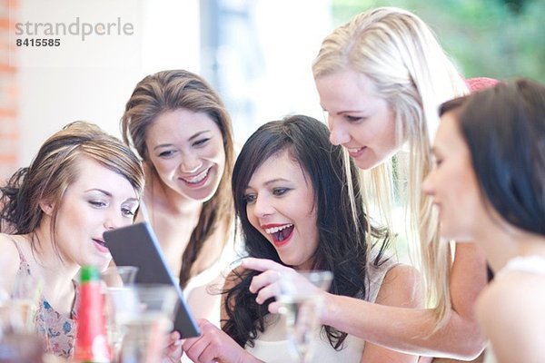 Weibliche Freunde lachen über digitales Tablett