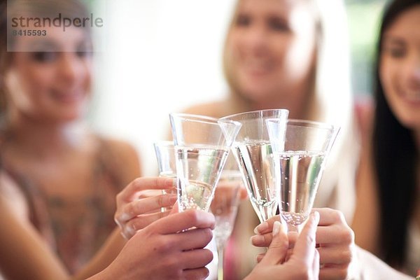Gruppe weiblicher Freunde  die mit einem Glas Champagner anstoßen.