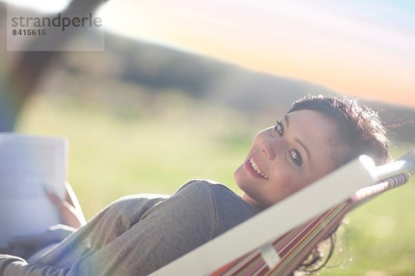 Junge Frau im Liegestuhl liegend mit Buch