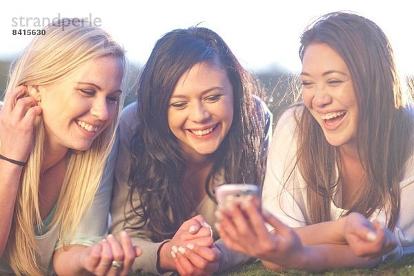 Drei junge Frauen auf dem Handy im Park