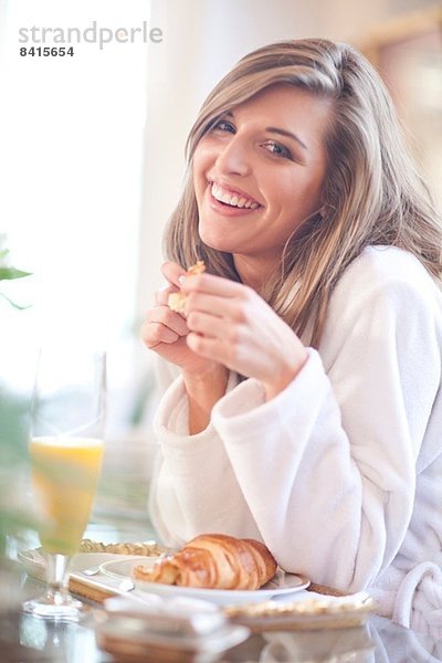 Porträt einer jungen Frau beim Frühstück im Bett