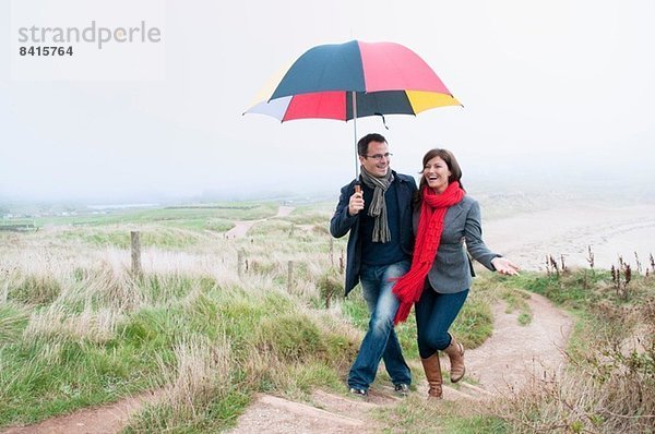 Paar auf Küstenwanderung mit Regenschirm  Thurlestone  Devon  UK