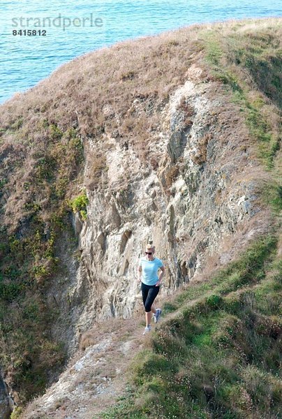 Mittlere erwachsene Frau beim Joggen an der Küste  Thurlestone  Devon  UK