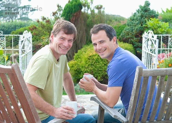 Zwei männliche erwachsene Freunde  die sich im Garten entspannen