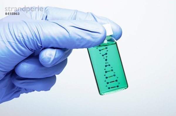 Biologische Forschung: Die Hand mit einem Nitrilhandschuh hält ein Fläschchen mit einem Modell eines DNA-Moleküls im Inneren.