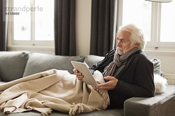 Senior Mann mit digitalem Tablett und Decke