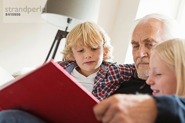 Großvater liest den Enkeln das Buch vor