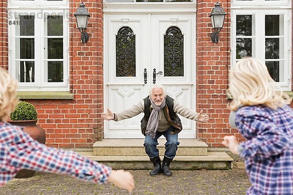 Großvater empfängt Enkelkinder mit offenen Armen