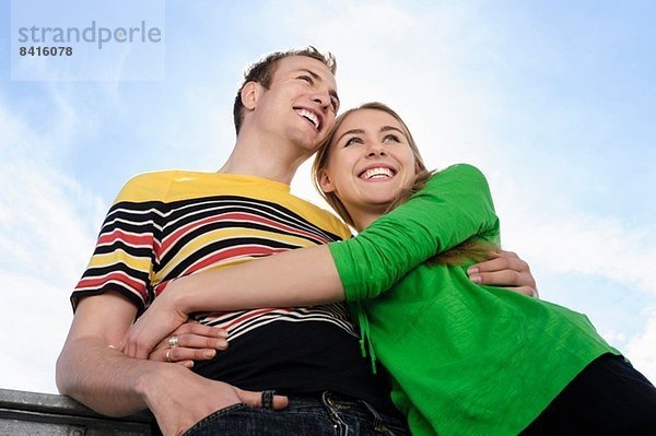 Porträt eines Paares mit lächelnden Armen um sich herum