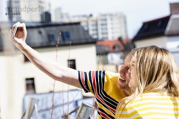 Junges Paar fotografiert sich auf dem Dach