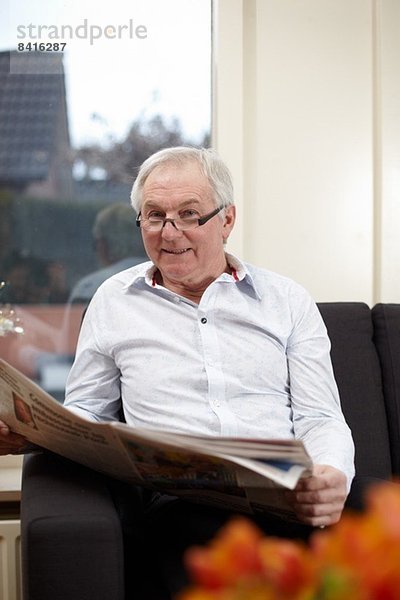 Senior Mann zu Hause Zeitung lesen
