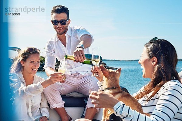 Mann gießt Champagner für junge Frauen auf dem Boot  Gavle  Schweden