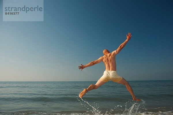 Mittlerer Erwachsener Mann  der über das Meer springt.