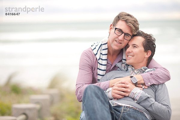 Schwules Paar umarmt sich am Strand