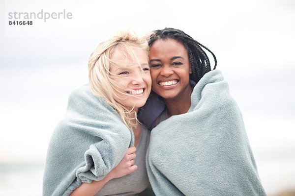 Schwules Paar in Decke gehüllt am Strand