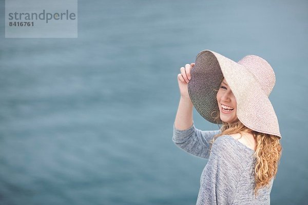 Frau mit Hut genießt das Meer