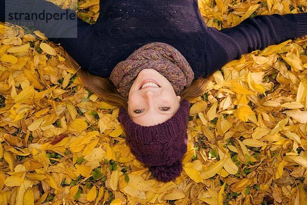 Junge Frau im Herbstlaub liegend