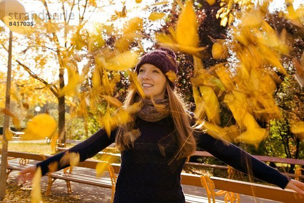 Junge Frau kotzt Herbstlaub im Park aus.