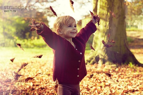 Kleinkind wirft Herbstlaub