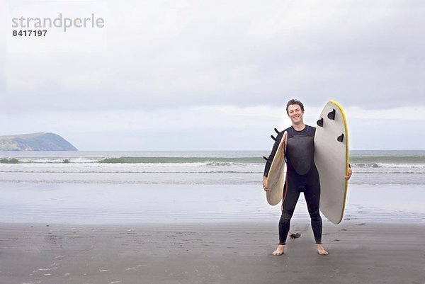 Porträt eines Mannes mit Surfbrettern am Strand