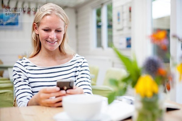 Junge Frau im Café mit Blick auf das Handy