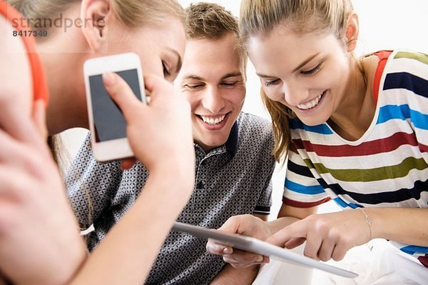 Drei junge erwachsene Freunde beim Betrachten des digitalen Tabletts