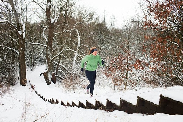 Läuferin  die im Winter die schneebedeckte Treppe hinaufsteigt
