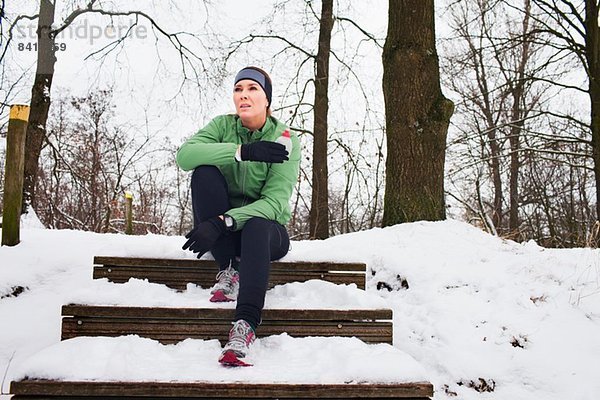 Läuferin entspannt sich im Winter auf der schneebedeckten Treppe