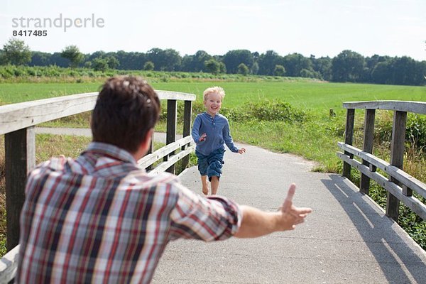 Junge rennt über Holzbrücke auf Papa zu