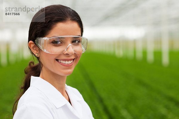 Wissenschaftler mit Schutzbrille vor Pflanzen im Gewächshaus