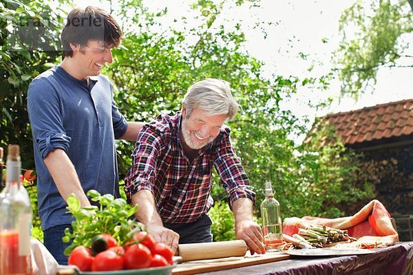 Vater und erwachsener Sohn machen Pizza