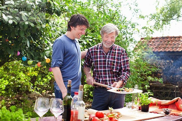 Vater und erwachsener Sohn machen Pizza