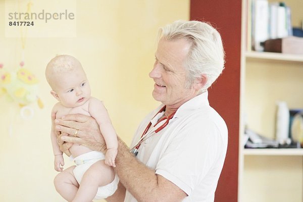 Pädiater untersucht Mädchen  hält Baby