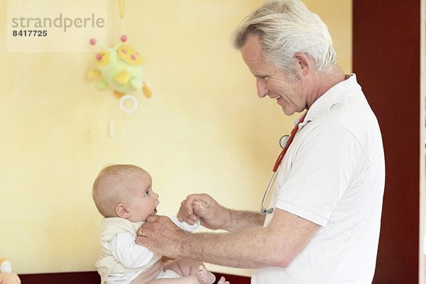 Kinderärztin untersucht das Mädchen  hält sich an den Händen