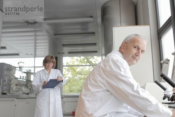 Wissenschaftler im Labor  Mann mit Mikroskop und Frau mit Notizen