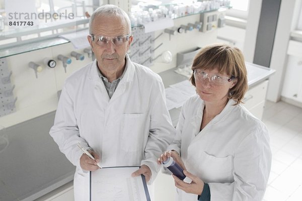 Im Labor arbeitende Wissenschaftler  die blaue Flüssigkeit in einem Fläschchen halten