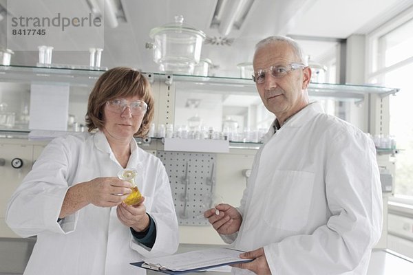 Im Labor arbeitende Wissenschaftler  die gelbe Flüssigkeit in einem Fläschchen halten