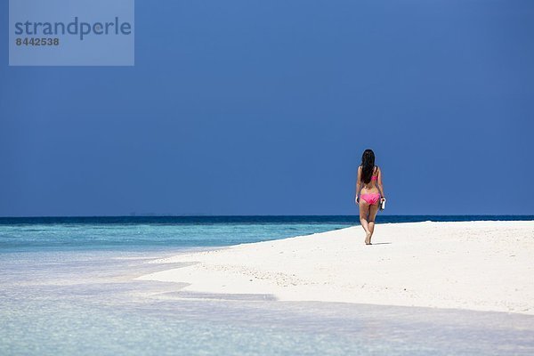 Malediven  Junge Frau im Bikini am Strand spazieren gehen