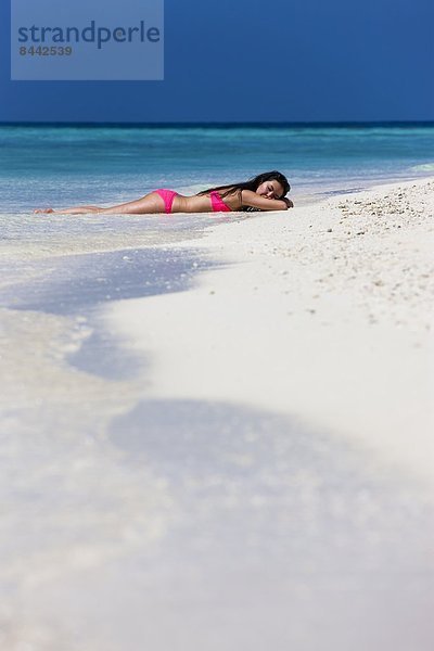 Maldives  Young woman in bikini lying in shallow water