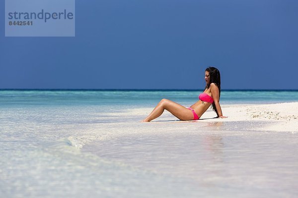 Maldives  Young woman in bikini sitting in shallow water