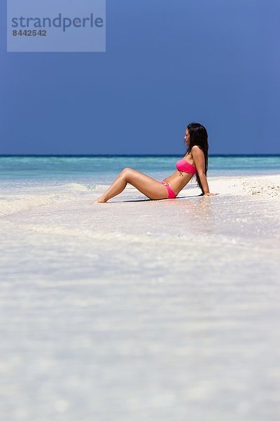 Maldives  Young woman in bikini sitting in shallow water
