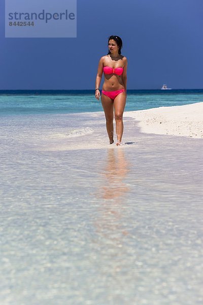 Malediven  Junge Frau im Bikini  die im flachen Wasser läuft