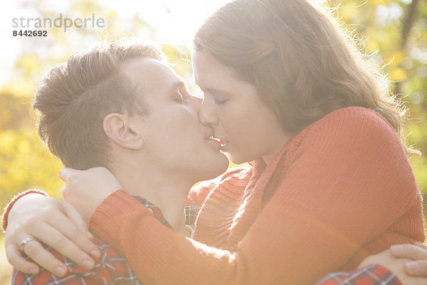 Happy young couple kissing in a park