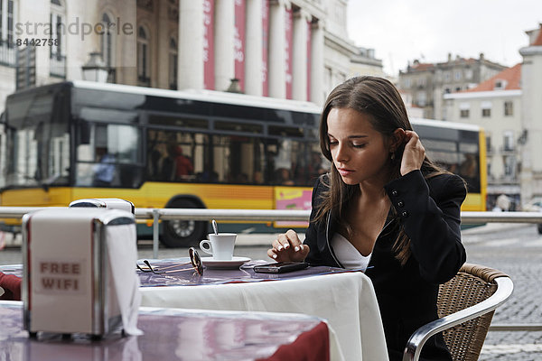 Portugal  Lisboa  Baixa  Rossio  Praca Dom Pedro IV  Teatro Nacional  junge Frau mit Smartphone im Straßencafé