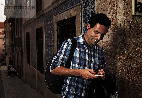 Portugal  Lisboa  Bairro Alto  junger Mann beim Blick auf sein Handy