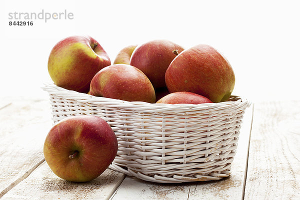 Apples (Malus) in white basket on wooden table