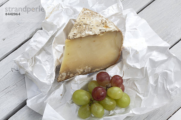 Sheep cheese and grapes on wooden table