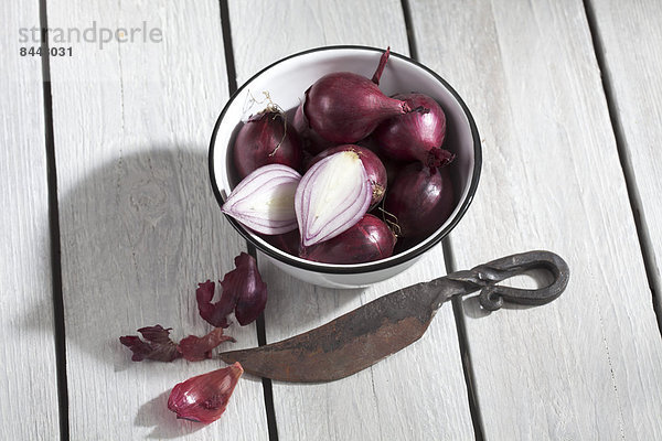Red pearl onions on wooden table
